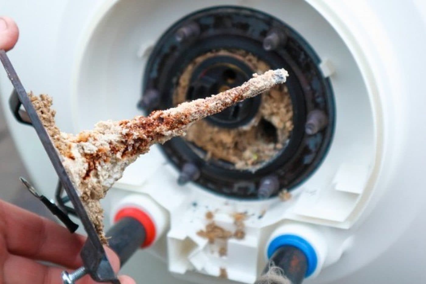 A water heater element pulled from the tank, thickly encrusted with hard scale and rust