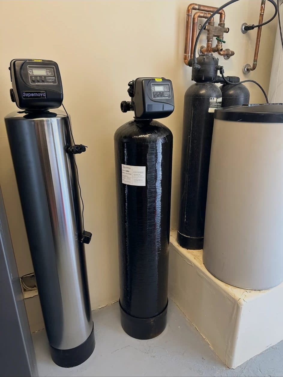 A complete multi-stage water treatment system installed in a garage: softener, filtration vessels and brine tank